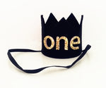 black crown with felt and the word ONE in gold glitter. There is an elastic band to keep headband on. 